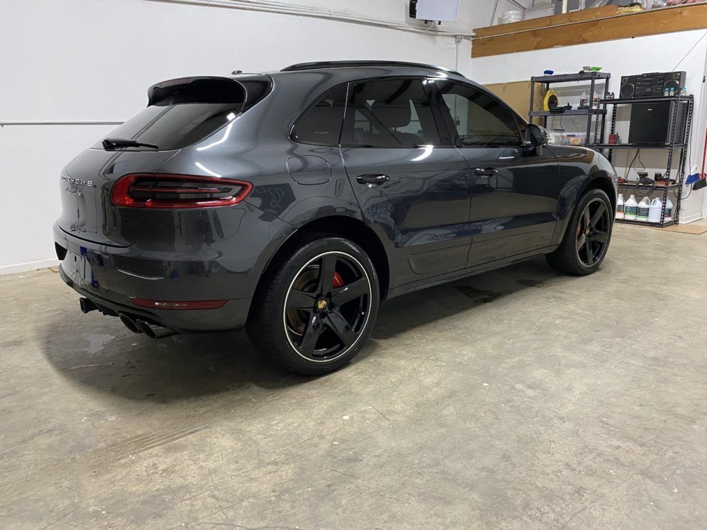 A gray porsche macan is parked in a garage.