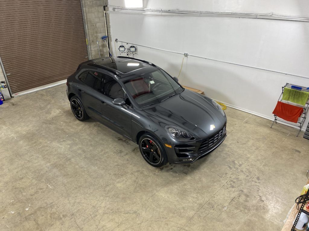 A gray porsche macan turbo is parked in a garage.