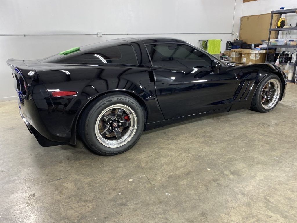 A black sports car is parked in a garage.