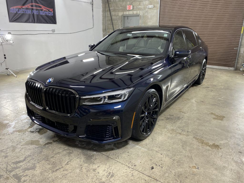 A black bmw 7 series is parked in a garage.