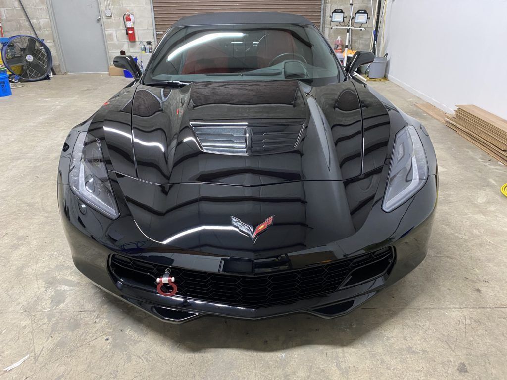 A black corvette convertible is parked in a garage.