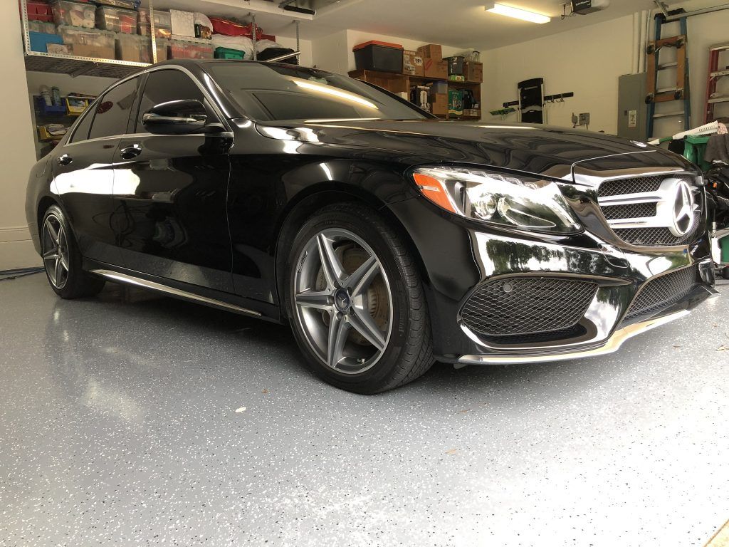 A black mercedes benz is parked in a garage.