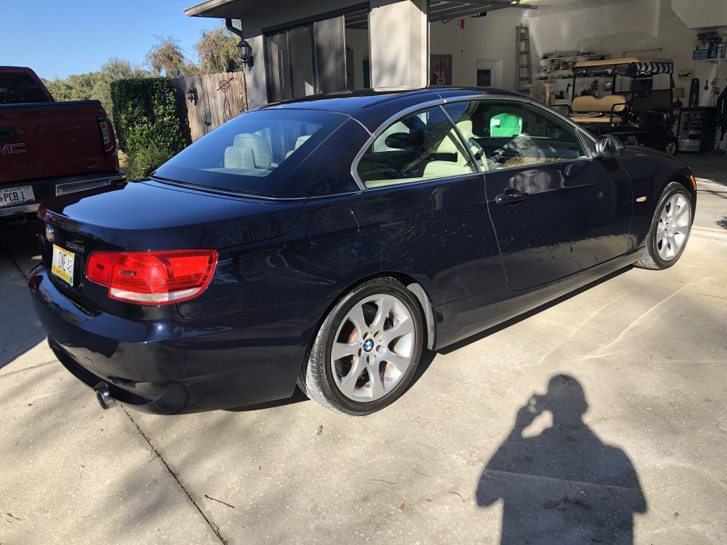 A black bmw is parked in a driveway in front of a garage.