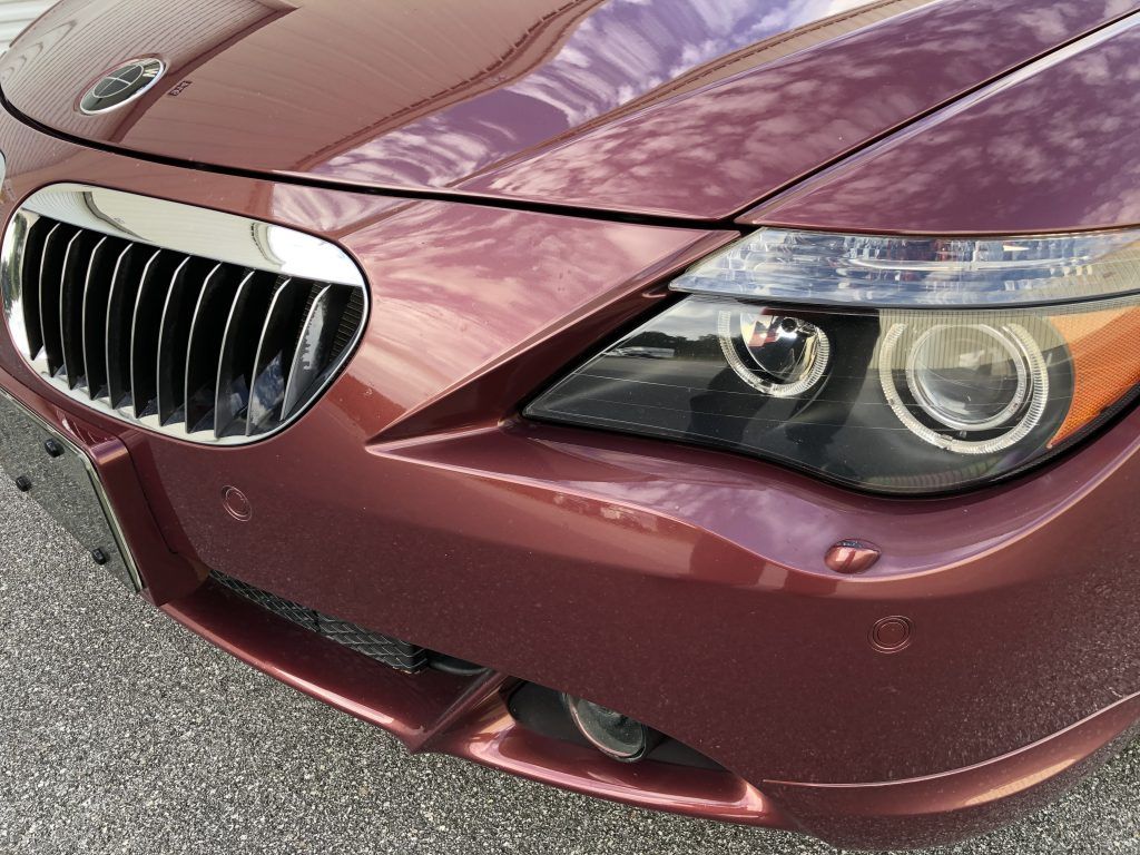 A red bmw is parked on the side of the road.