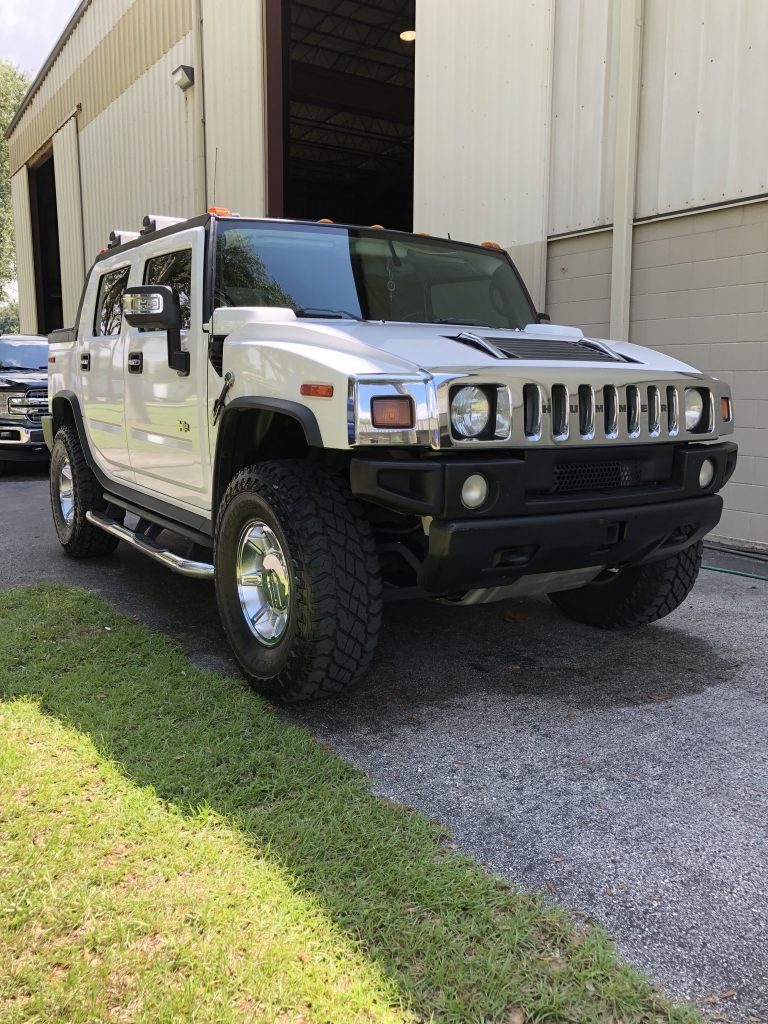 A white hummer h2 is parked in front of a building.