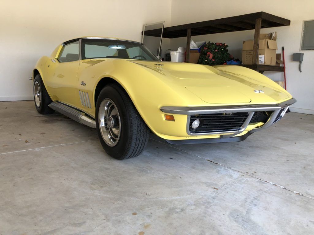 A yellow corvette is parked in a garage.
