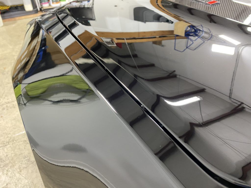 A close up of a black car 's hood in a garage