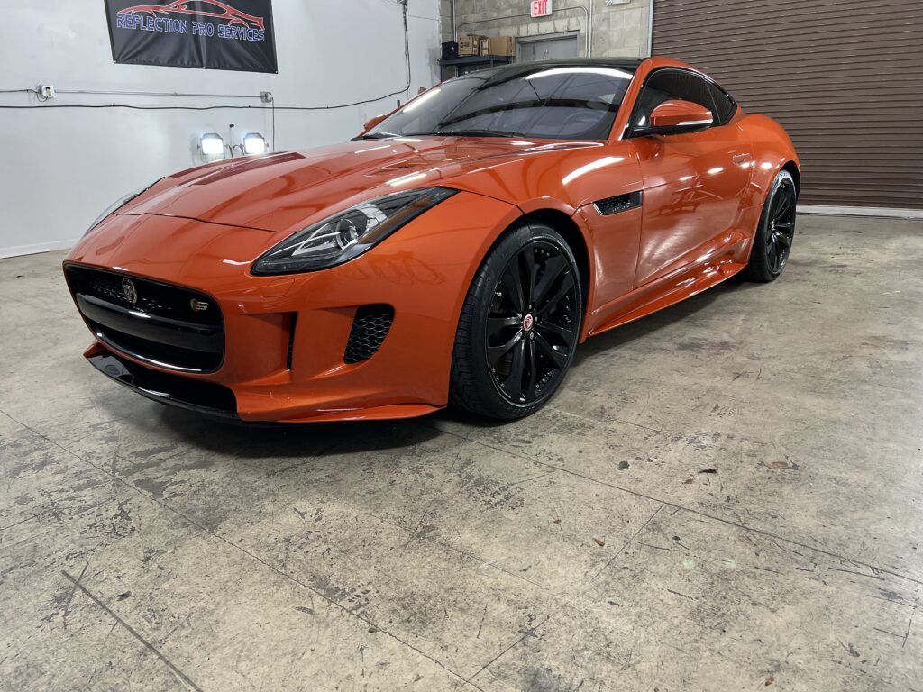 A red jaguar f type is parked in a garage.