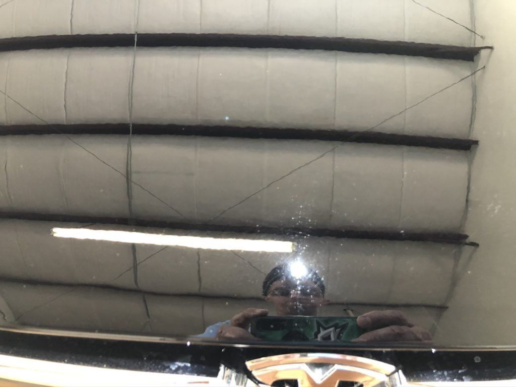 A man is taking a picture of himself in the mirror of a car.