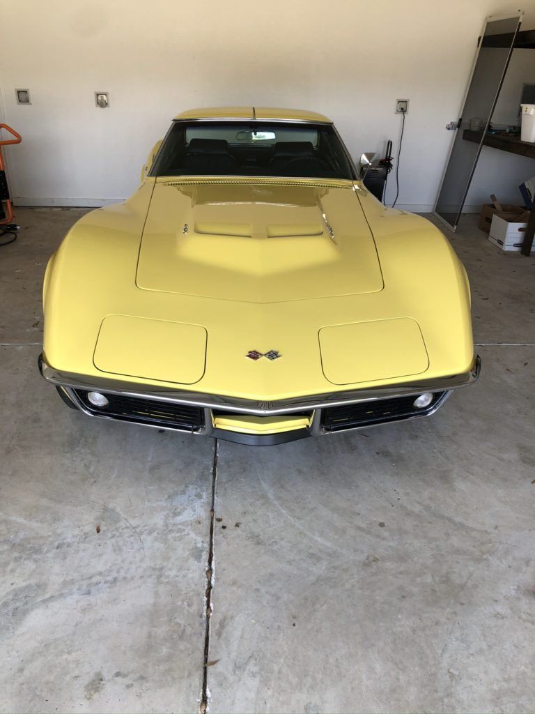 A yellow corvette is parked in a garage.