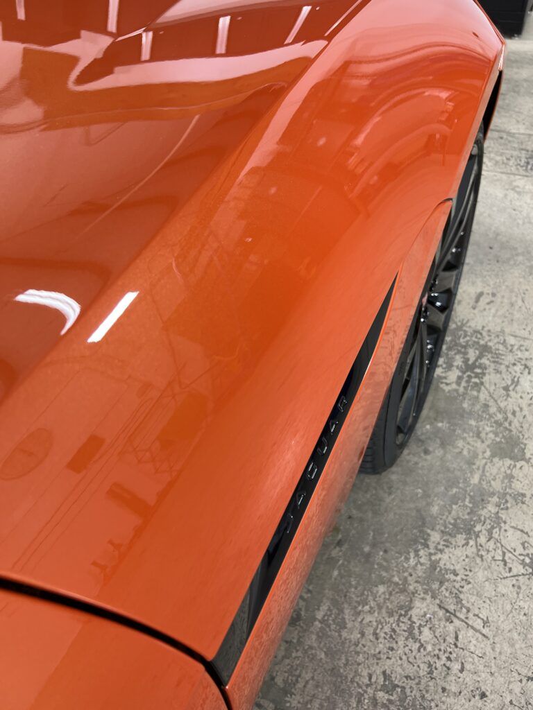 A close up of the side of an orange sports car.