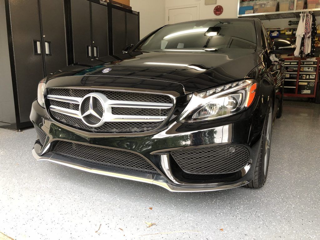 A black mercedes benz is parked in a garage.