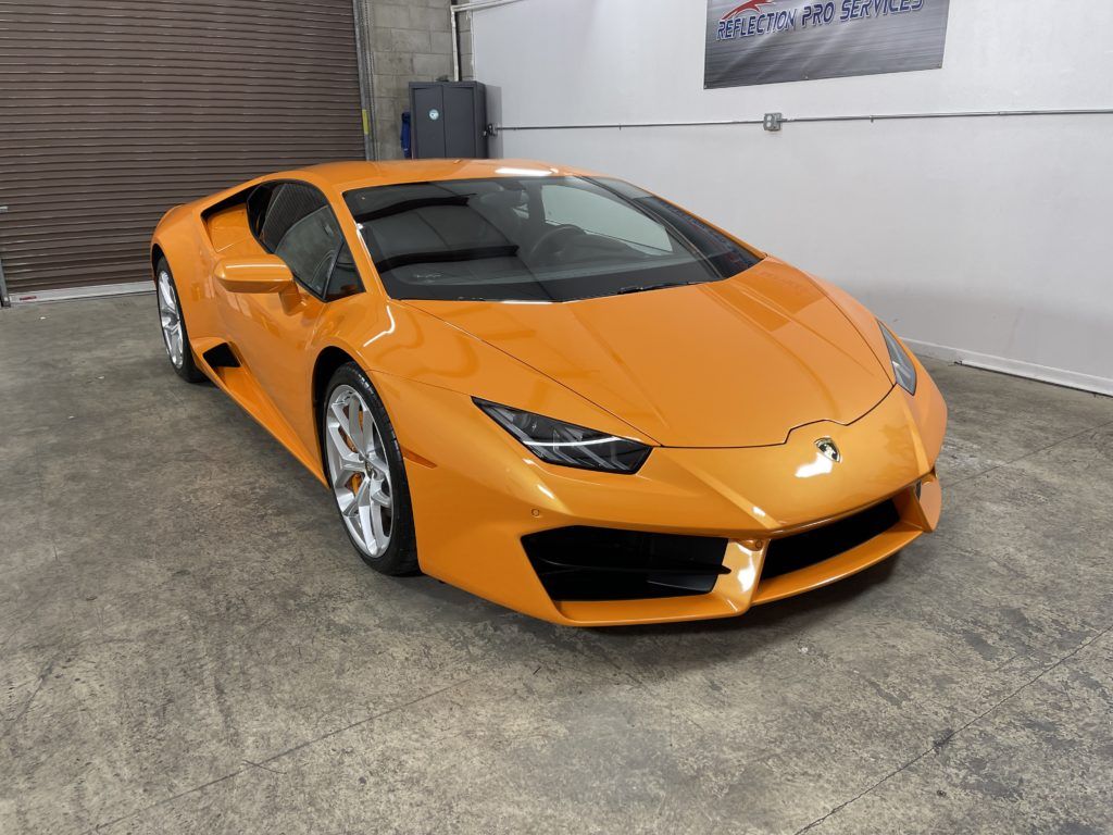 An orange lamborghini huracan is parked in a garage.