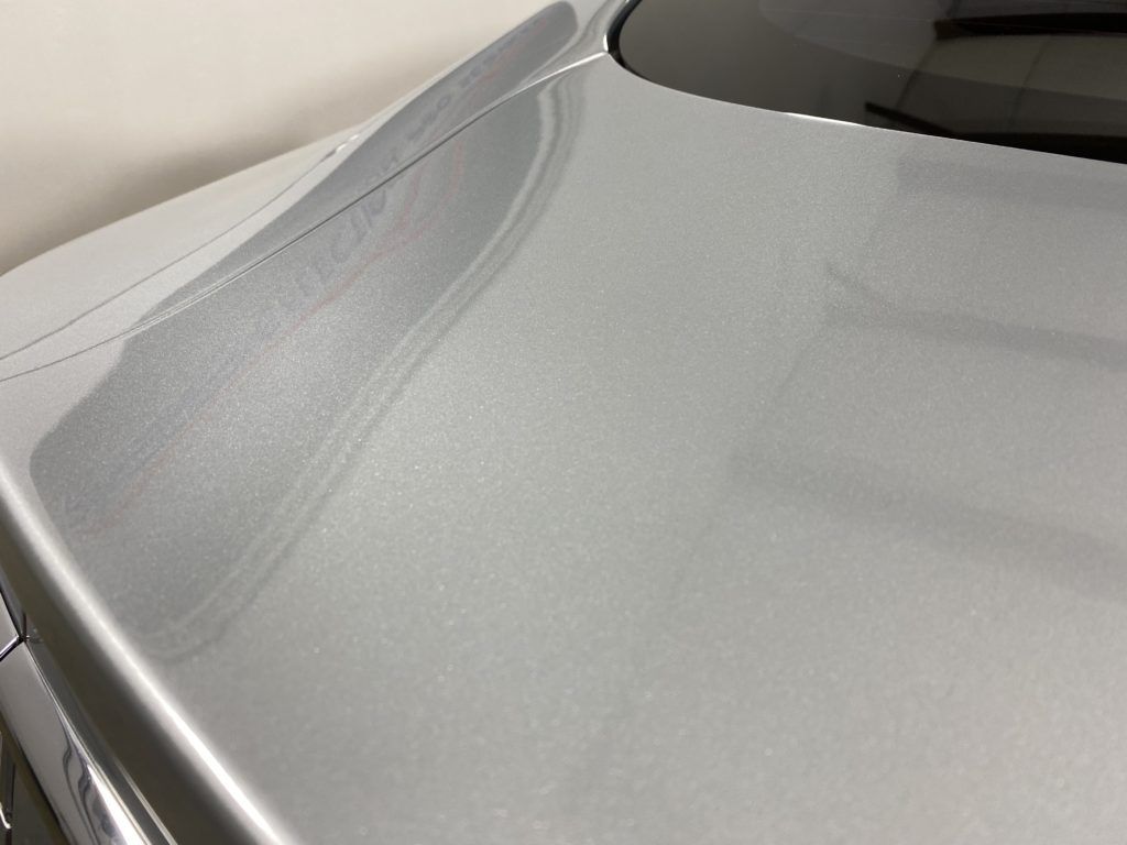 A close up of the hood of a silver car.