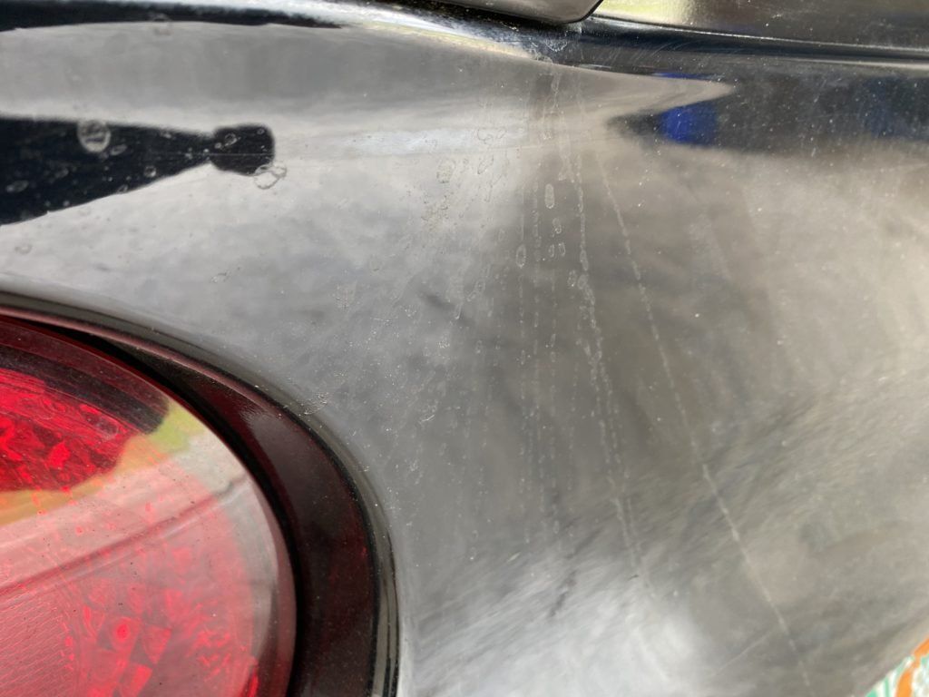 A close up of a black car with a red tail light.