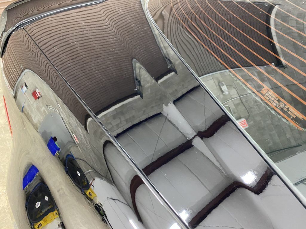 A close up of a car 's windshield with a reflection of a building in it.
