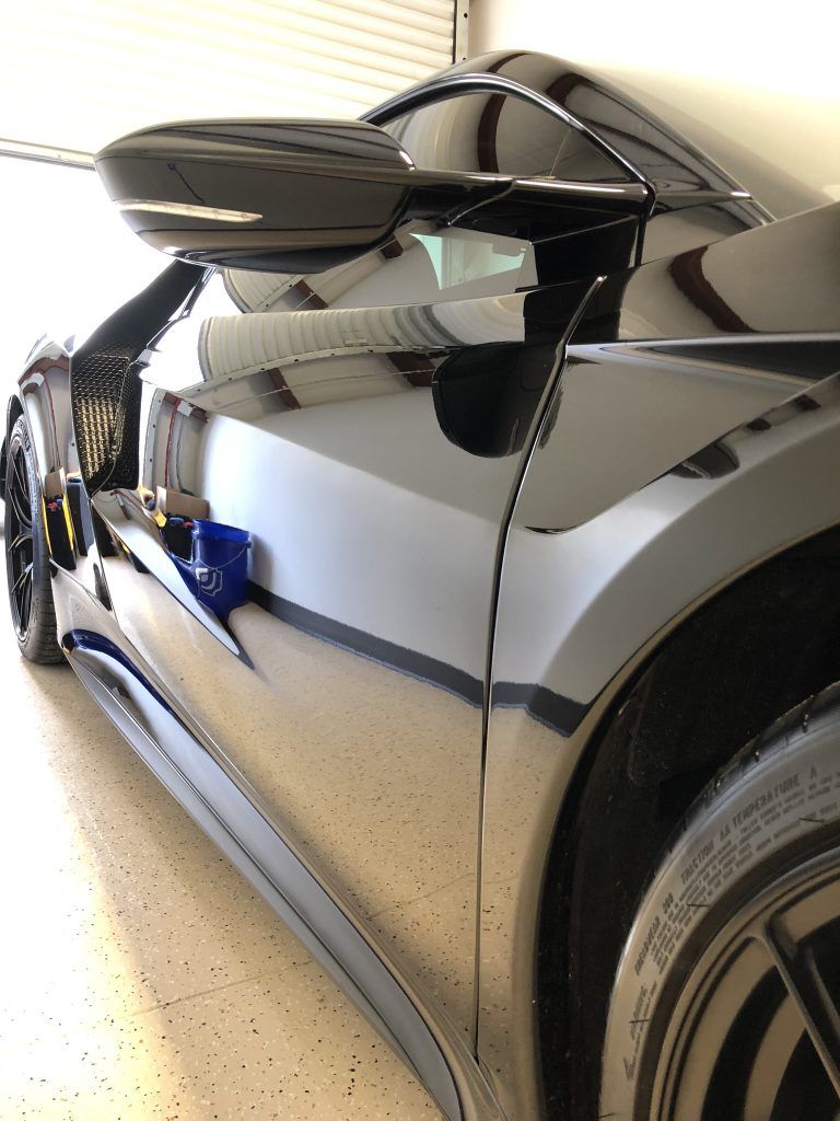 A black sports car is parked in a garage.