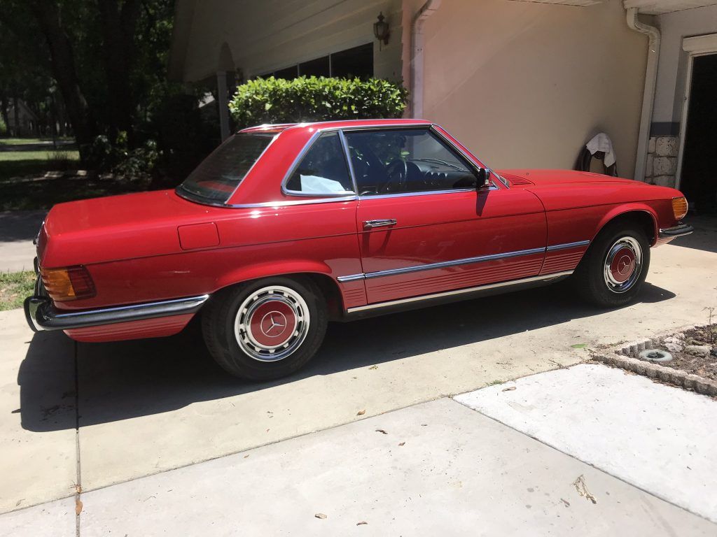 A red car is parked in front of a house