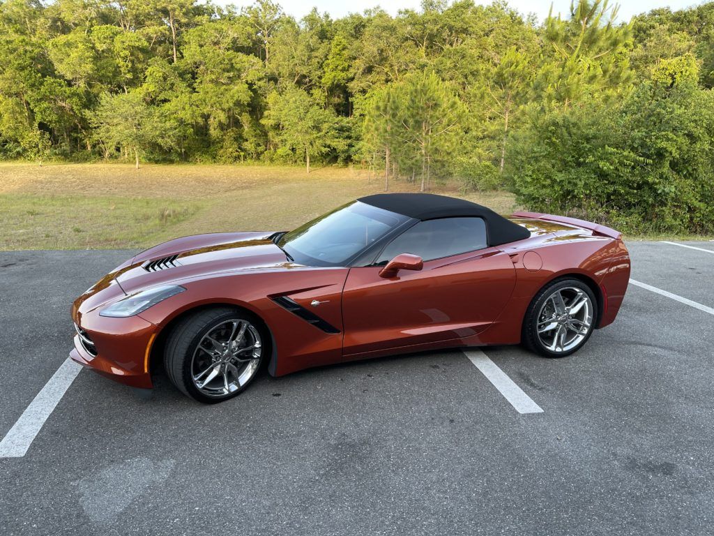 A red corvette convertible is parked in a parking lot.