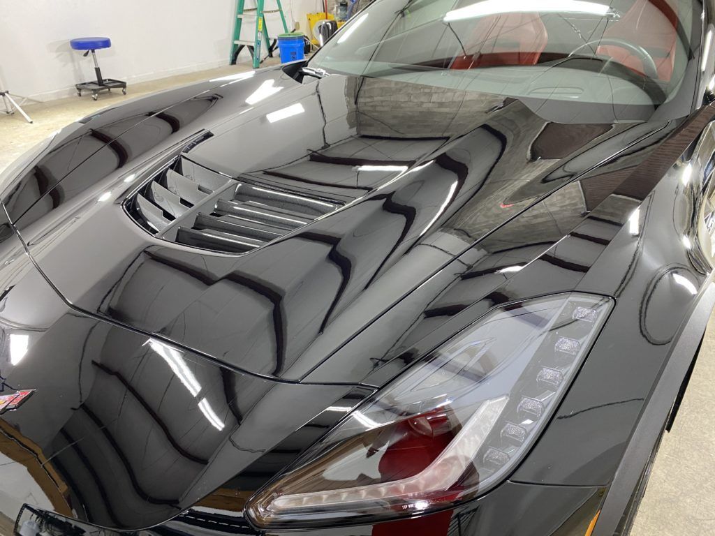 A black sports car is parked in a garage.