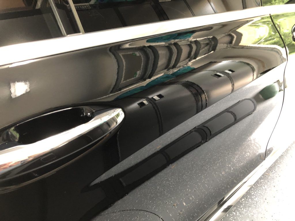 A close up of a car door with a reflection of a train in it