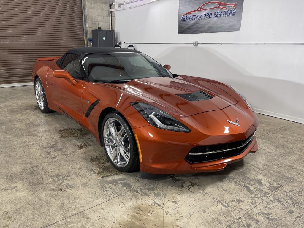 A red corvette convertible is parked in a garage.