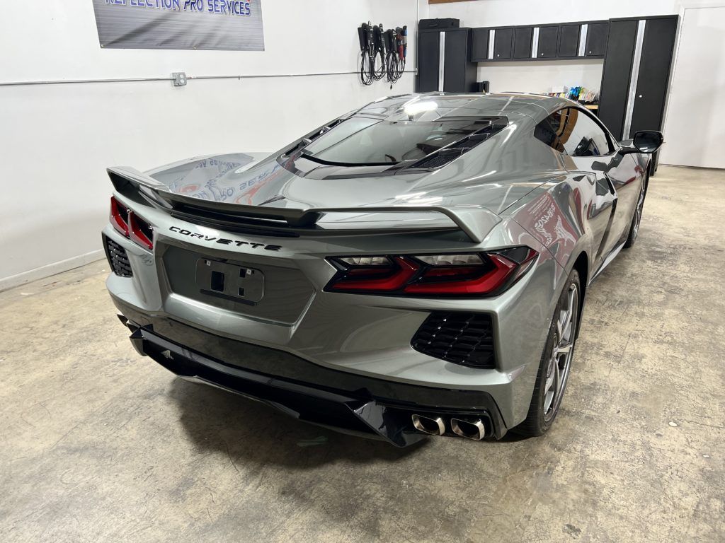A silver corvette is parked in a garage.