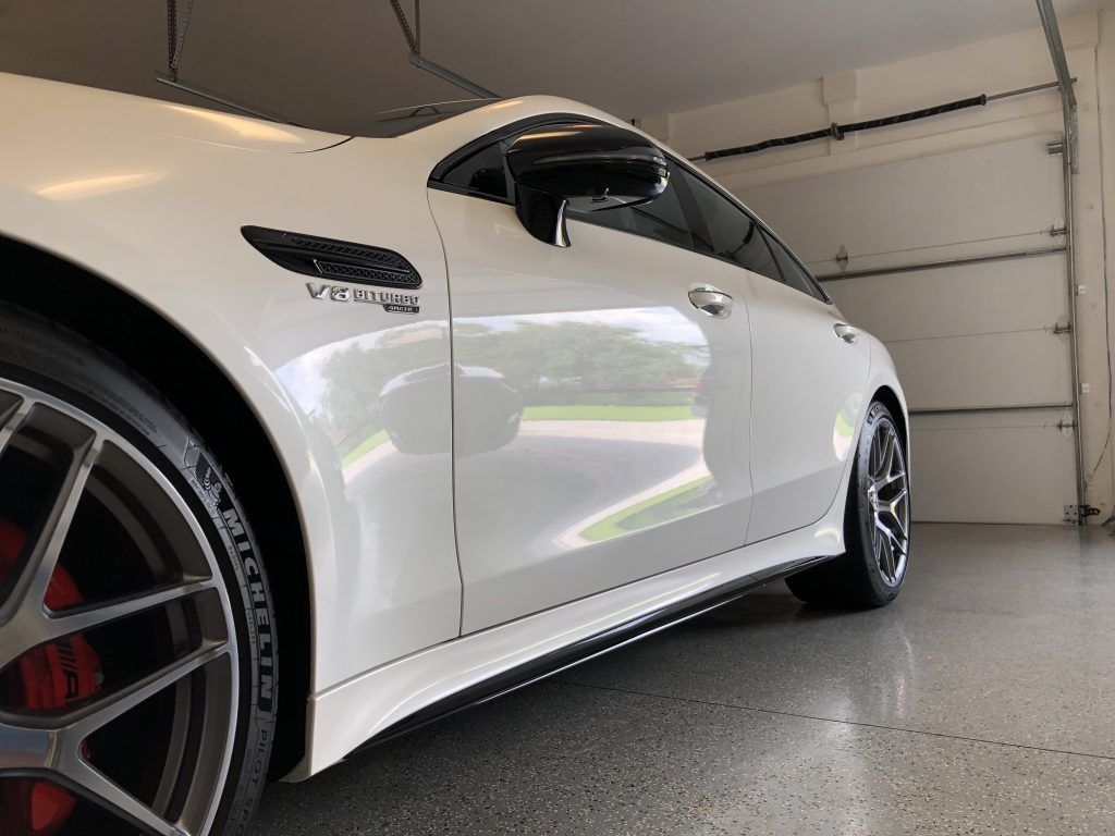 A white car is parked in a garage next to a garage door.
