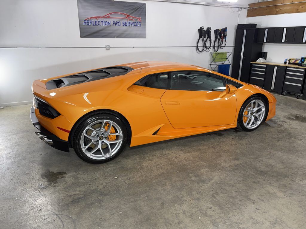 An orange lamborghini huracan is parked in a garage.