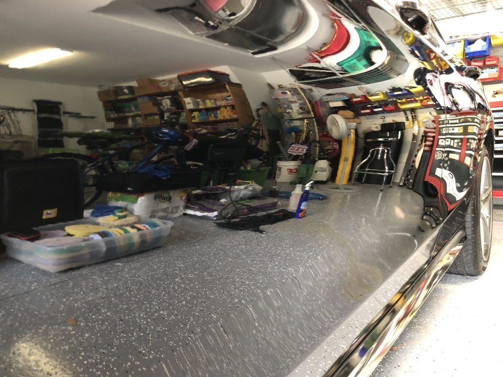 A motorcycle is parked in a garage with a lot of tools on the floor.