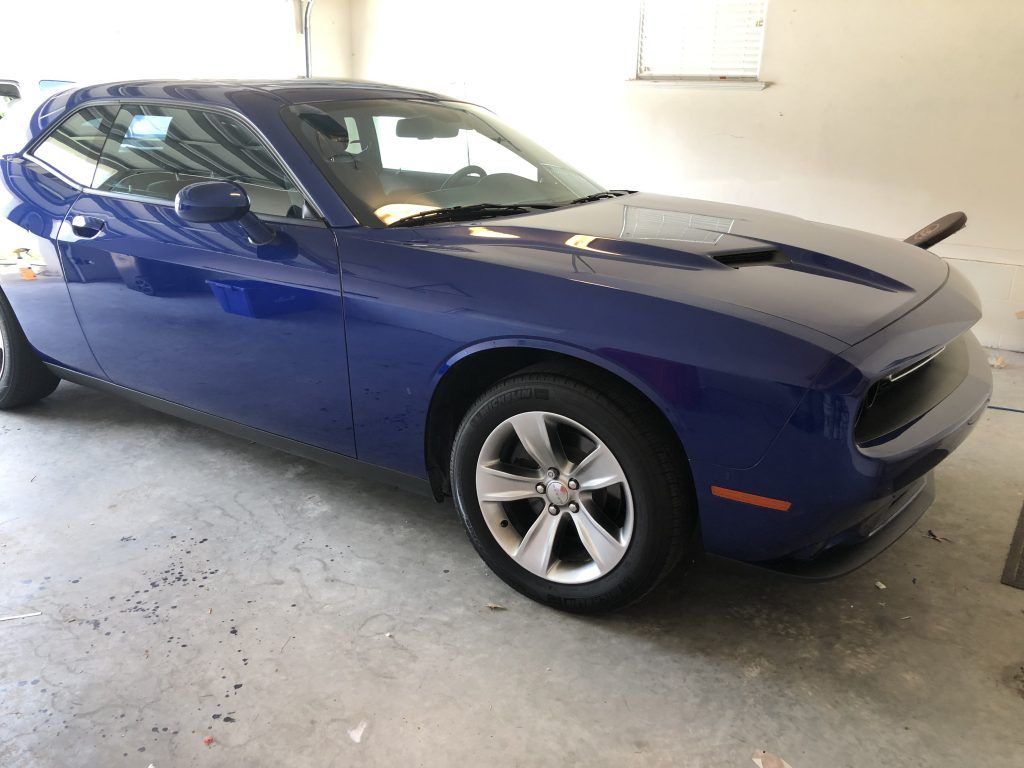 A blue dodge challenger is parked in a garage.