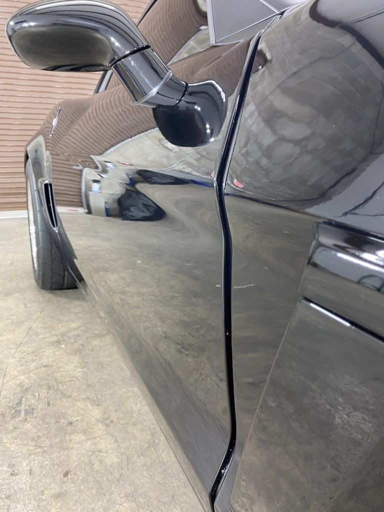 A close up of a black car parked in a garage.