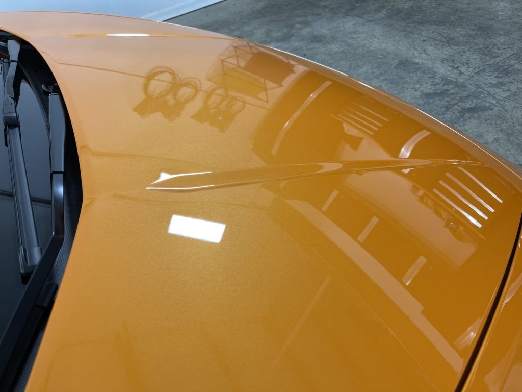 A close up of the hood of an orange car