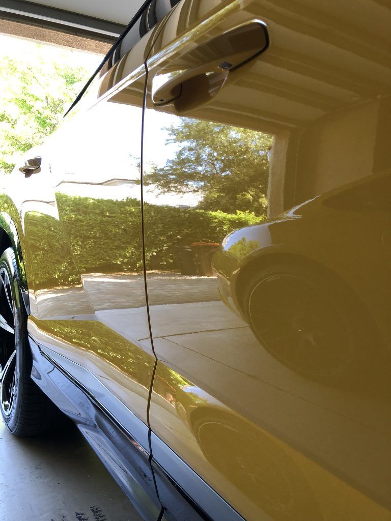 A yellow car is parked in a garage with the door open.