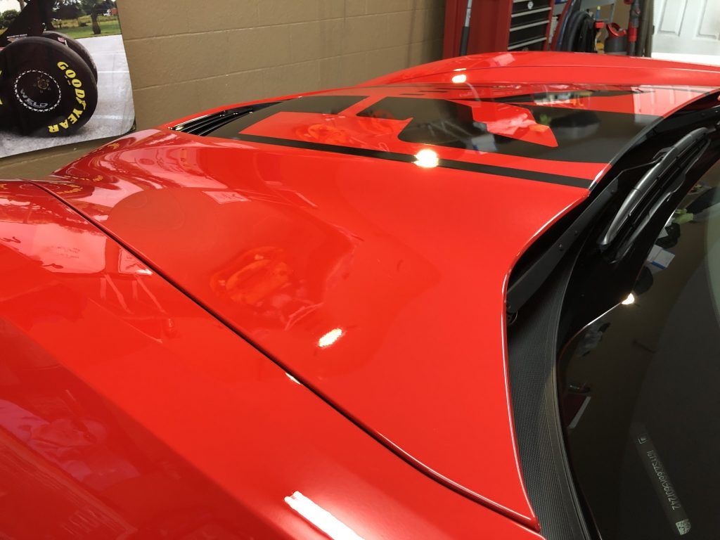A red car with black stripes on the hood