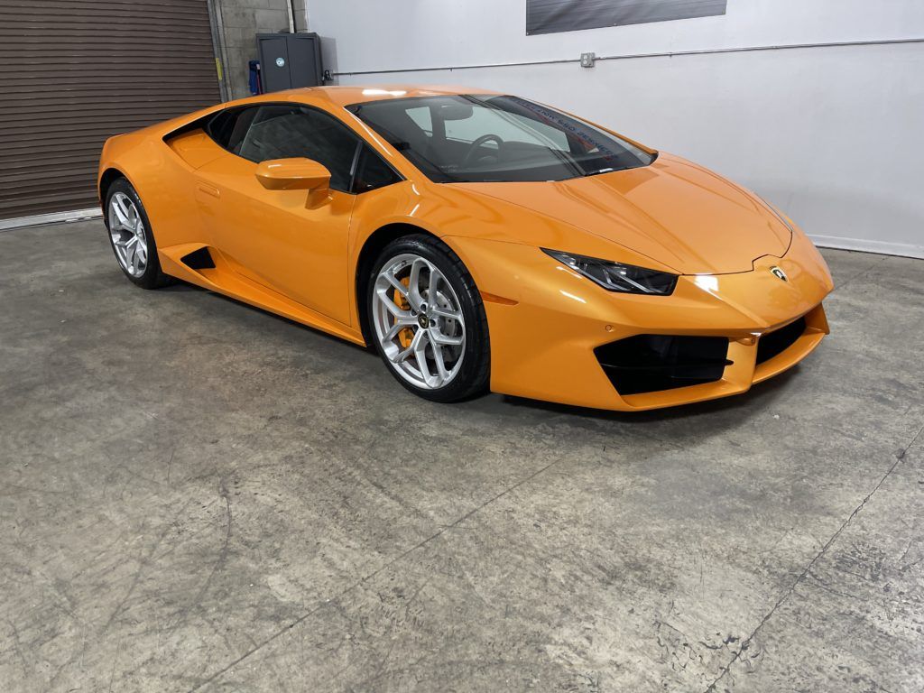 An orange lamborghini huracan is parked in a garage.