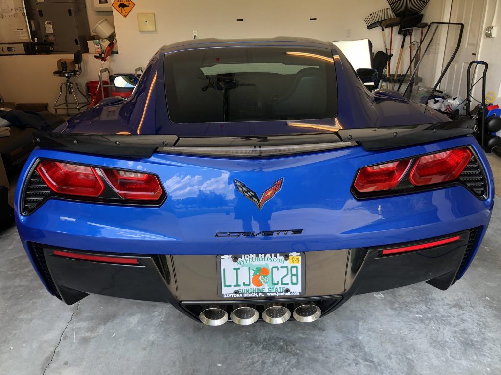 A blue corvette is parked in a garage with a license plate that says ljc28