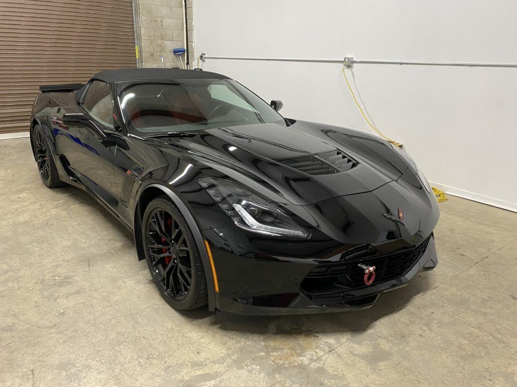 A black corvette zr1 convertible is parked in a garage.
