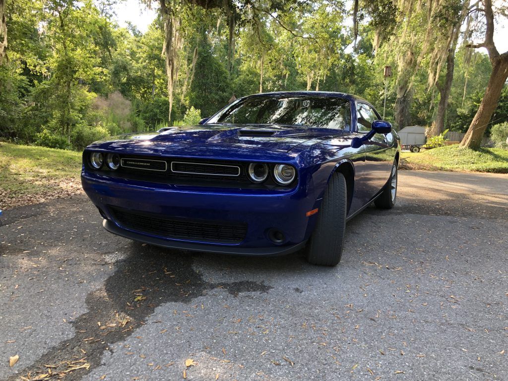 A blue dodge challenger is parked on the side of the road.