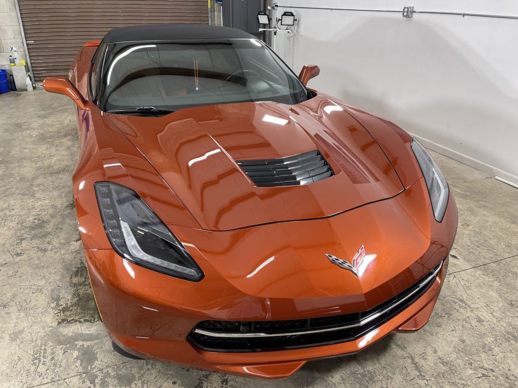 A red corvette convertible is parked in a garage.