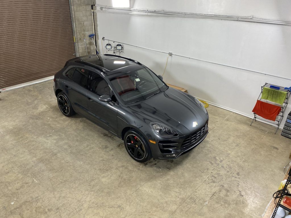 A gray porsche macan turbo is parked in a garage.