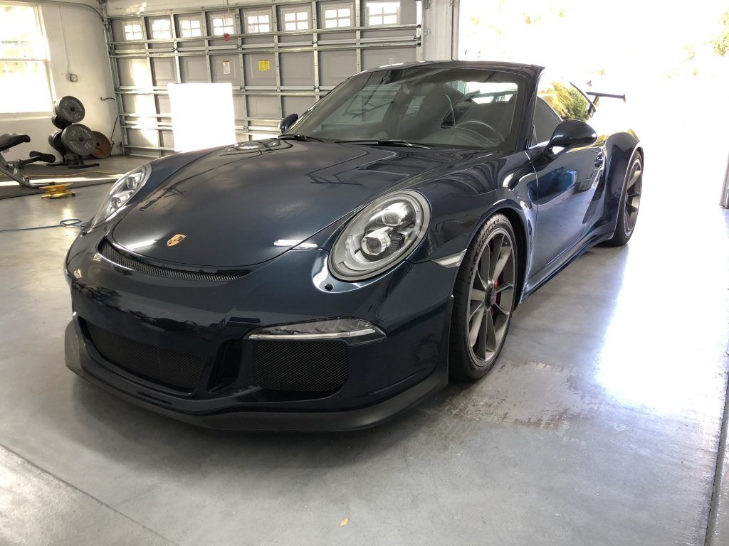 A black porsche 911 convertible is parked in a garage.