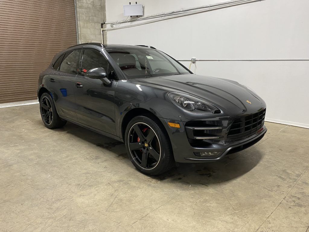 A gray porsche macan turbo is parked in a garage.