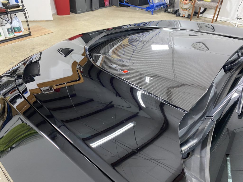 A close up of the hood of a black car in a garage.