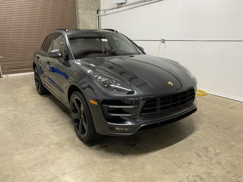 A black porsche macan turbo is parked in a garage.