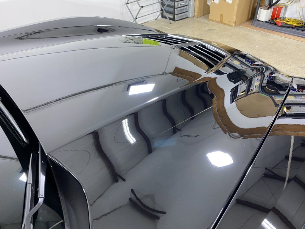 A close up of a car 's hood in a garage.