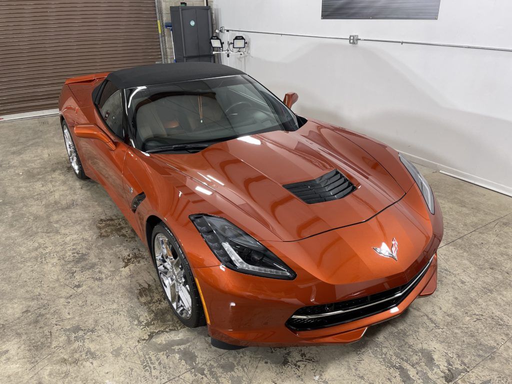 A red corvette convertible is parked in a garage.