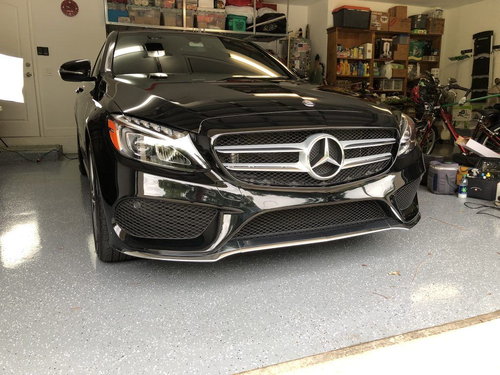 A black mercedes benz is parked in a garage.