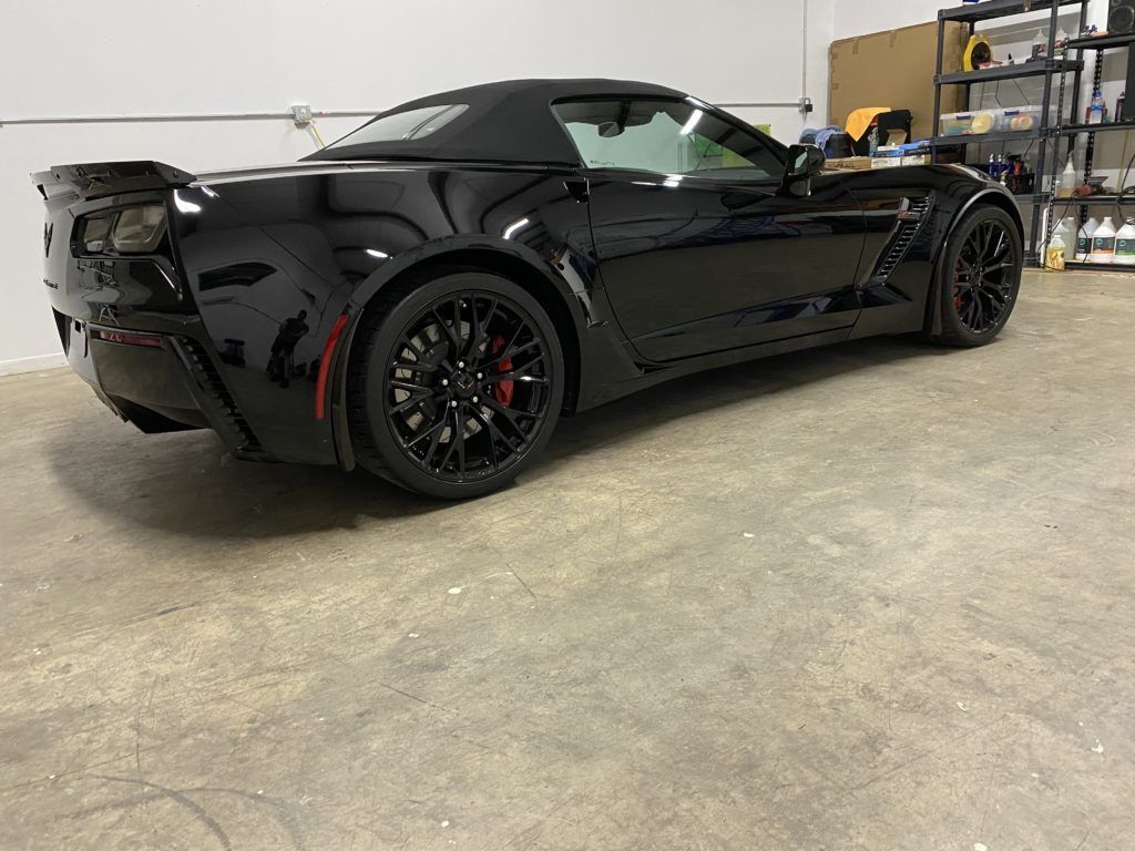A black corvette convertible is parked in a garage.