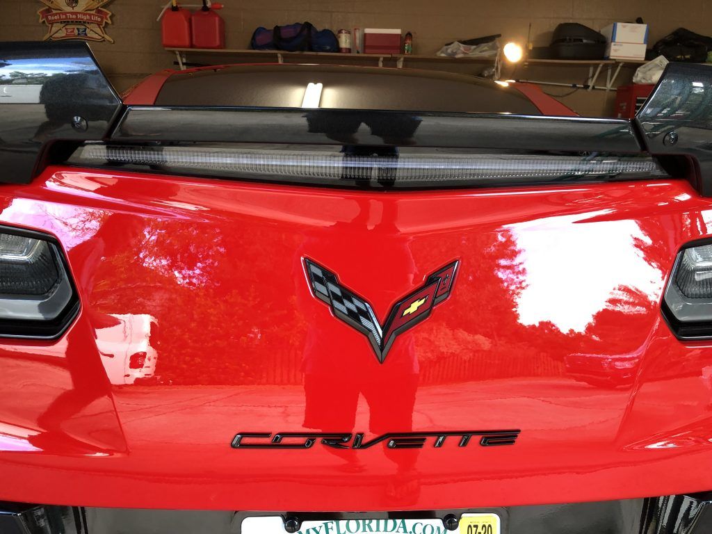 A red corvette is parked in a garage.